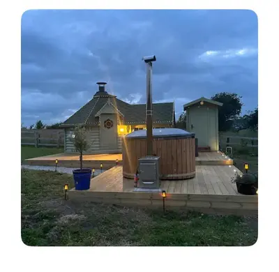 a wooden deck with a hot tub in front of a house at Off GRID Hobbit Hut with Wood Burning Hot tub NO SHOWER in Hapton
