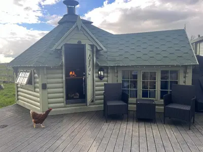 a chicken standing on a deck with a house at Off GRID Hobbit Hut with Wood Burning Hot tub NO SHOWER in Hapton