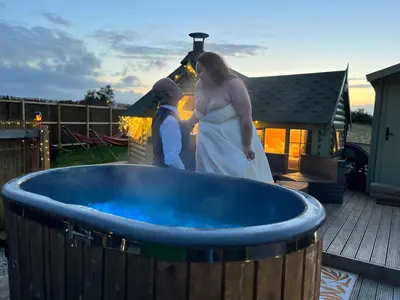a bride and groom standing next to a large tub at Off GRID Hobbit Hut with Wood Burning Hot tub NO SHOWER in Hapton