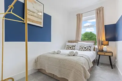 a bedroom with a bed with a blue wall at Beautiful House - Sleeps up to 7 - Free Parking, Fast Wifi and Smart TV by Yoko Property in Wigan