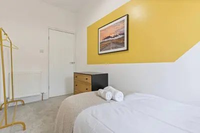 a bedroom with a white bed and a yellow wall at Beautiful House - Sleeps up to 7 - Free Parking, Fast Wifi and Smart TV by Yoko Property in Wigan