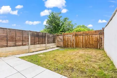 a wooden fence in a yard next to a sidewalk at Beautiful House - Sleeps up to 7 - Free Parking, Fast Wifi and Smart TV by Yoko Property in Wigan