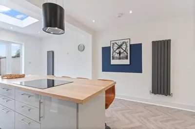 a kitchen with white cabinets and a wooden counter top at Beautiful House - Sleeps up to 7 - Free Parking, Fast Wifi and Smart TV by Yoko Property in Wigan