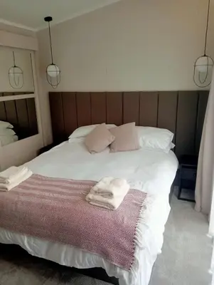 a bedroom with a white bed with two towels on it at Lake View Lodge in Lytham St Annes