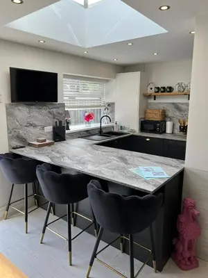 a kitchen with a large marble counter top and black chairs at Beachside Suites - HOT TUB sleeps 10 in Blackpool