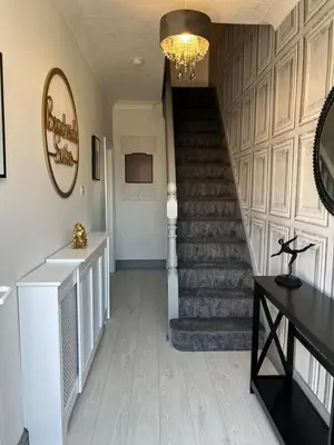 a hallway with a staircase with a chandelier at Beachside Suites - HOT TUB sleeps 10 in Blackpool