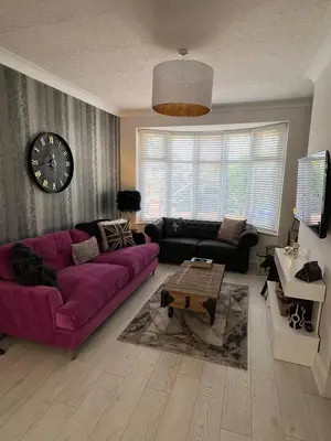 a living room with a purple couch and a clock at Beachside Suites - HOT TUB sleeps 10 in Blackpool