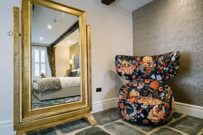 a bedroom with a chair and a mirror at Aynsome Manor in Cartmel