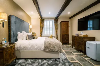 a bedroom with a bed and a dresser and a television at Aynsome Manor in Cartmel