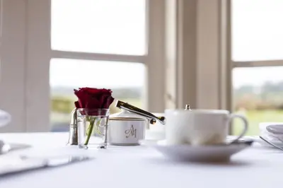 a table with a flower and a cup of coffee at Aynsome Manor in Cartmel