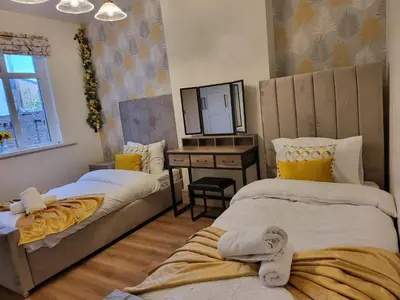 a room with two beds and a desk and a mirror at Country Style Modern Self Catering 3 Bedroom Bungalow in Blackpool in Blackpool