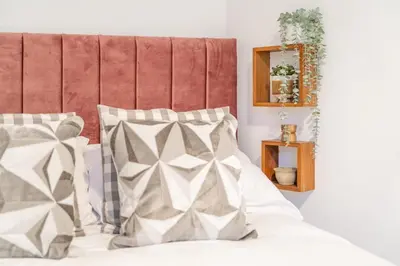 a bed with white and grey pillows and a red headboard at Fabulous New 1 Bedroom Ground Floor Flat in Morecambe