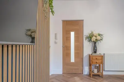 a hallway with a wooden door and a vase of flowers at Fabulous New 1 Bedroom Ground Floor Flat in Morecambe