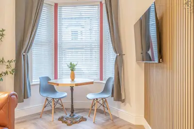 a table and chairs in a room with a window at Fabulous New 1 Bedroom Ground Floor Flat in Morecambe