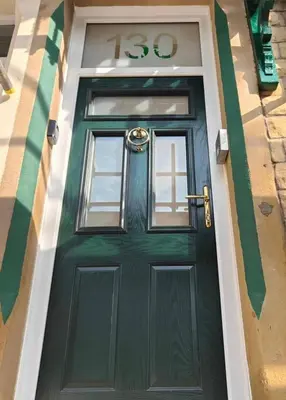 a green door on a building with a sign on it at Fabulous New 1 Bedroom Ground Floor Flat in Morecambe