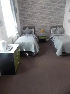 a bedroom with two beds and a brick wall at The Celtic Pride Hotel in Blackpool