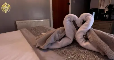 a bed with a pair of swan towels on it at The Celtic Pride Hotel in Blackpool