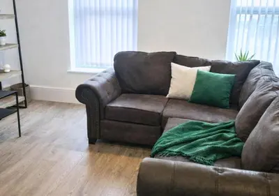 a brown couch with green pillows in a living room at Williamson Suites - Apartment 1 in Liverpool
