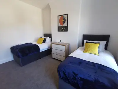 a bedroom with two beds and a nightstand and sidx sidx sidx sidx at Comfy and Cozy 3 Bed house, free parking & Wifi in Birkenhead