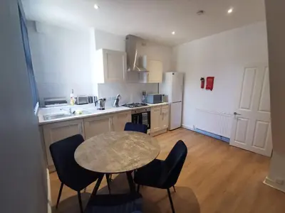 a kitchen with a table and chairs in a kitchen at Comfy and Cozy 3 Bed house, free parking & Wifi in Birkenhead