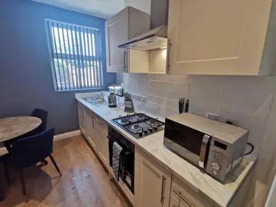 a kitchen with a microwave and a stove top oven at Comfy and Cozy 3 Bed house, free parking & Wifi in Birkenhead