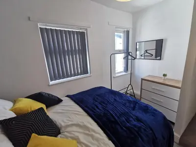 a bedroom with a bed and a dresser and a window at Comfy and Cozy 3 Bed house, free parking & Wifi in Birkenhead