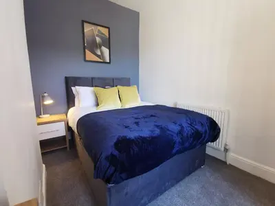 a bedroom with a bed with a blue comforter at Comfy and Cozy 3 Bed house, free parking & Wifi in Birkenhead