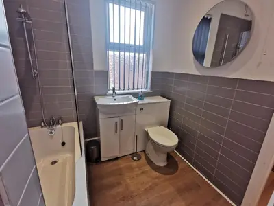 a bathroom with a toilet and a sink and a mirror at Comfy and Cozy 3 Bed house, free parking & Wifi in Birkenhead