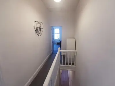 a hallway with a white wall and a refrigerator at Comfy and Cozy 3 Bed house, free parking & Wifi in Birkenhead