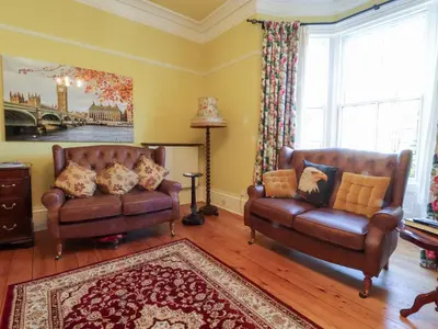a living room with two leather couches and a rug at Mullans in Southport