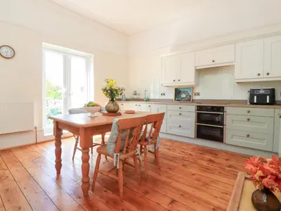 a kitchen with a wooden table and chairs in a room at Mullans in Southport