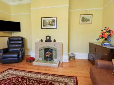 a living room with a fireplace and a chair at Mullans in Southport