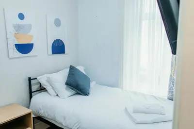 a bedroom with a bed with a blue pillow and a window at Glen Allan Hotel in Blackpool