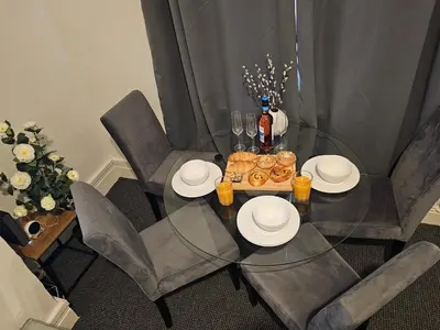 a dining table with two chairs and a table with plates and drinks at Convenient 3 bed, Pr1 near Uclan n Train station in Preston