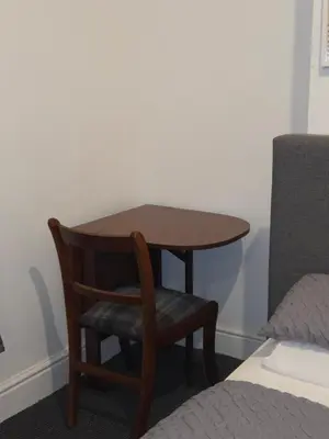 a wooden table and a chair next to a bed at Convenient 3 bed, Pr1 near Uclan n Train station in Preston