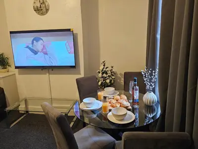 a dining room with a table and a tv at Convenient 3 bed, Pr1 near Uclan n Train station in Preston