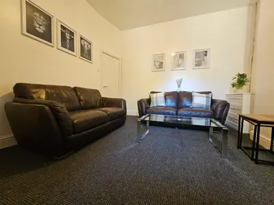 a living room with a leather couch and a glass table at Convenient 3 bed, Pr1 near Uclan n Train station in Preston