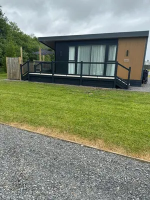 a small black house with a grass yard at luxury hot tub glamping apartment in Ireleth