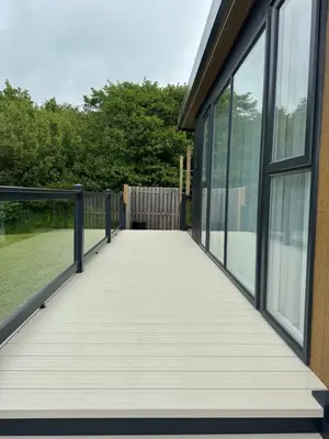 a boardwalk leading to a building with windows at luxury hot tub glamping apartment in Ireleth