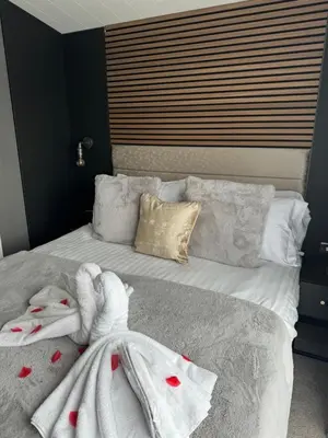 a bedroom with a bed with white blankets and pillows at luxury hot tub glamping apartment in Ireleth