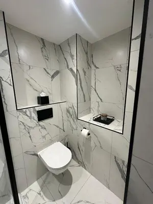 a white bathroom with a toilet and a mirror at Secret Suites in Lancaster