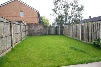 a backyard with a wooden fence and green grass at Quiet 3 bed house, pet friendly in Kirkby