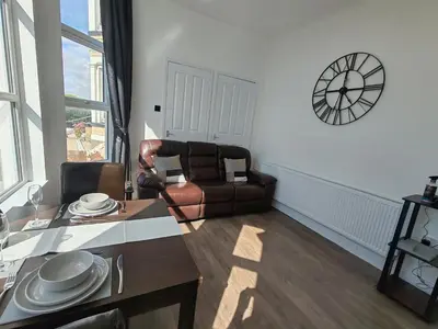 a living room with a table and a leather chair at Lakeside View in Southport