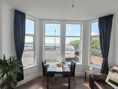 a living room with a table and some windows at Lakeside View in Southport