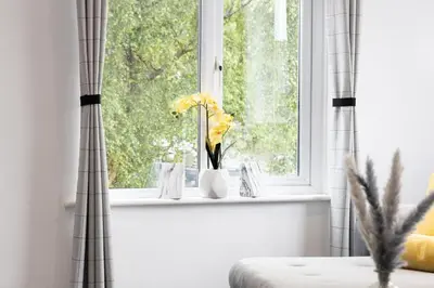 a window with flowers in vases on a window sill at Cozy Boutique Studios Perfect for Contractors & Travelers in Bolton