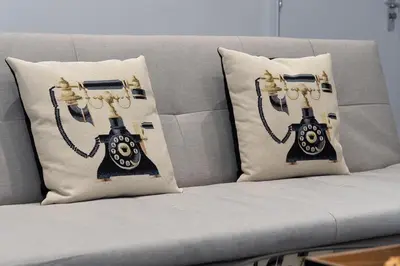 a couch with two pillows with a phone on it at Cozy Boutique Studios Perfect for Contractors & Travelers in Bolton