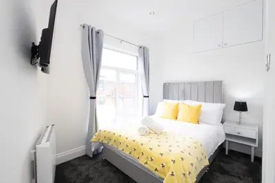 a bedroom with a bed with yellow pillows and a window at Cozy Boutique Studios Perfect for Contractors & Travelers in Bolton