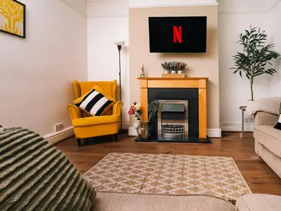 a living room with a fireplace and a yellow chair at Beautiful Home Away From Home - 3 Bedrooms - 6 Beds - Sleeps 7 - Free Parking in Liverpool