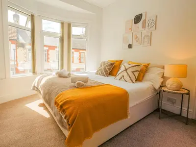 a bedroom with a bed with an orange blanket on it at Beautiful Home Away From Home - 3 Bedrooms - 6 Beds - Sleeps 7 - Free Parking in Liverpool