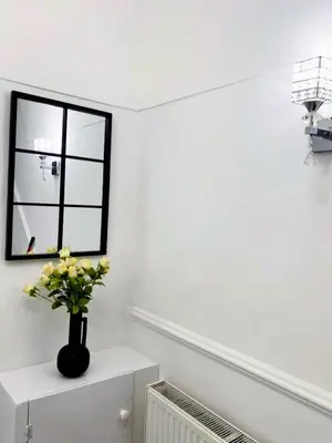 a white room with a vase of flowers on a shelf at Modernised 3 Bed House in Liverpool
